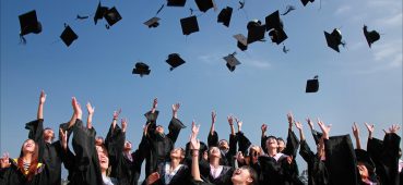 Photo showing graduates throwing caps in the air.