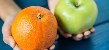 LMS vs Exam Software comparing apples and oranges, picture of a person holding an apple and an orange.